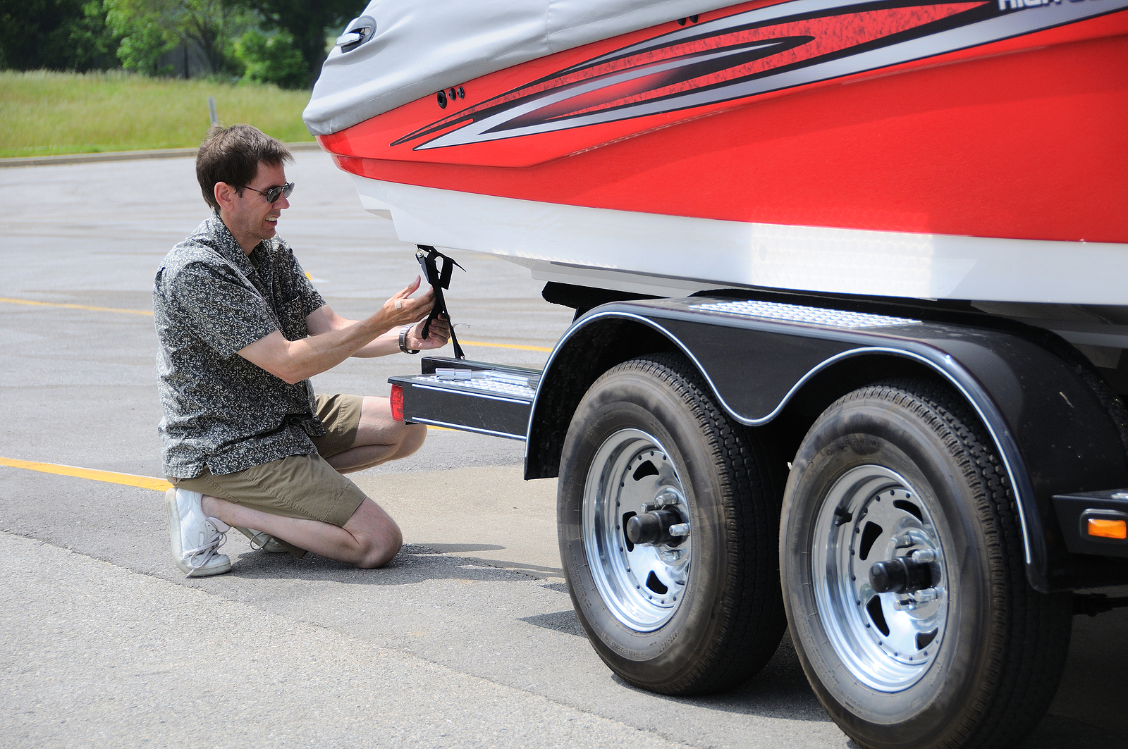 trailer service and repair - A Man Adjusting Tie Down Straps On Boat Trailer